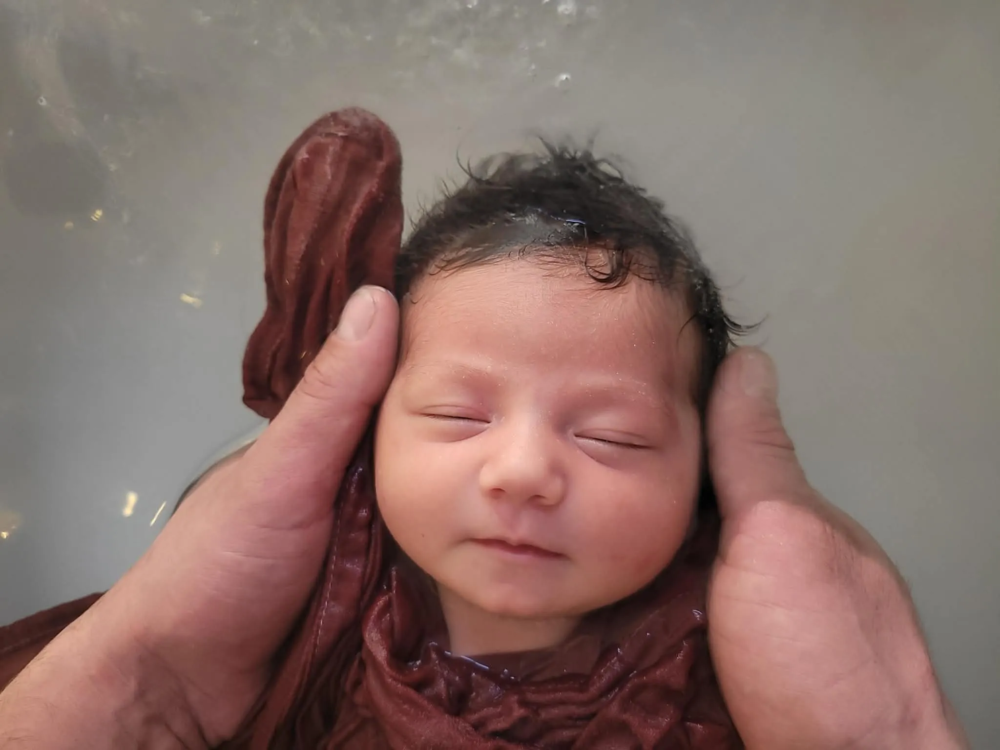 Bébé profondément endormi, soutenu dans les mains de Joanne