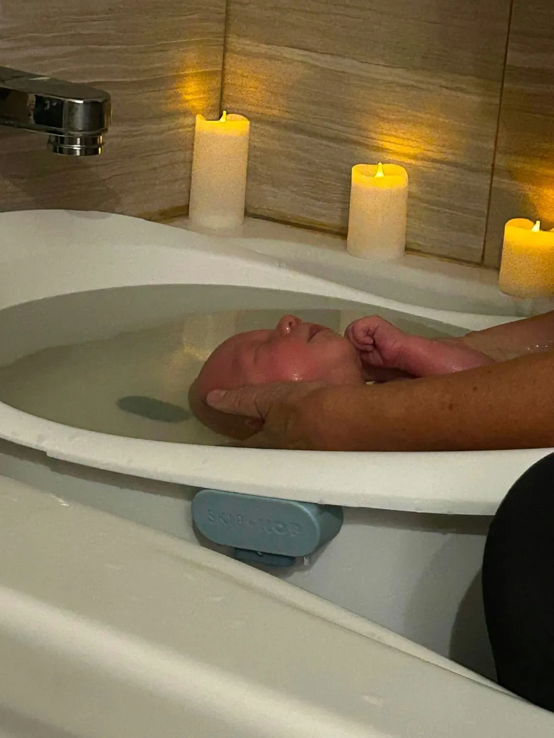 Bébé détendu, la tête dans la main de Joanne, à la surface de l'eau
